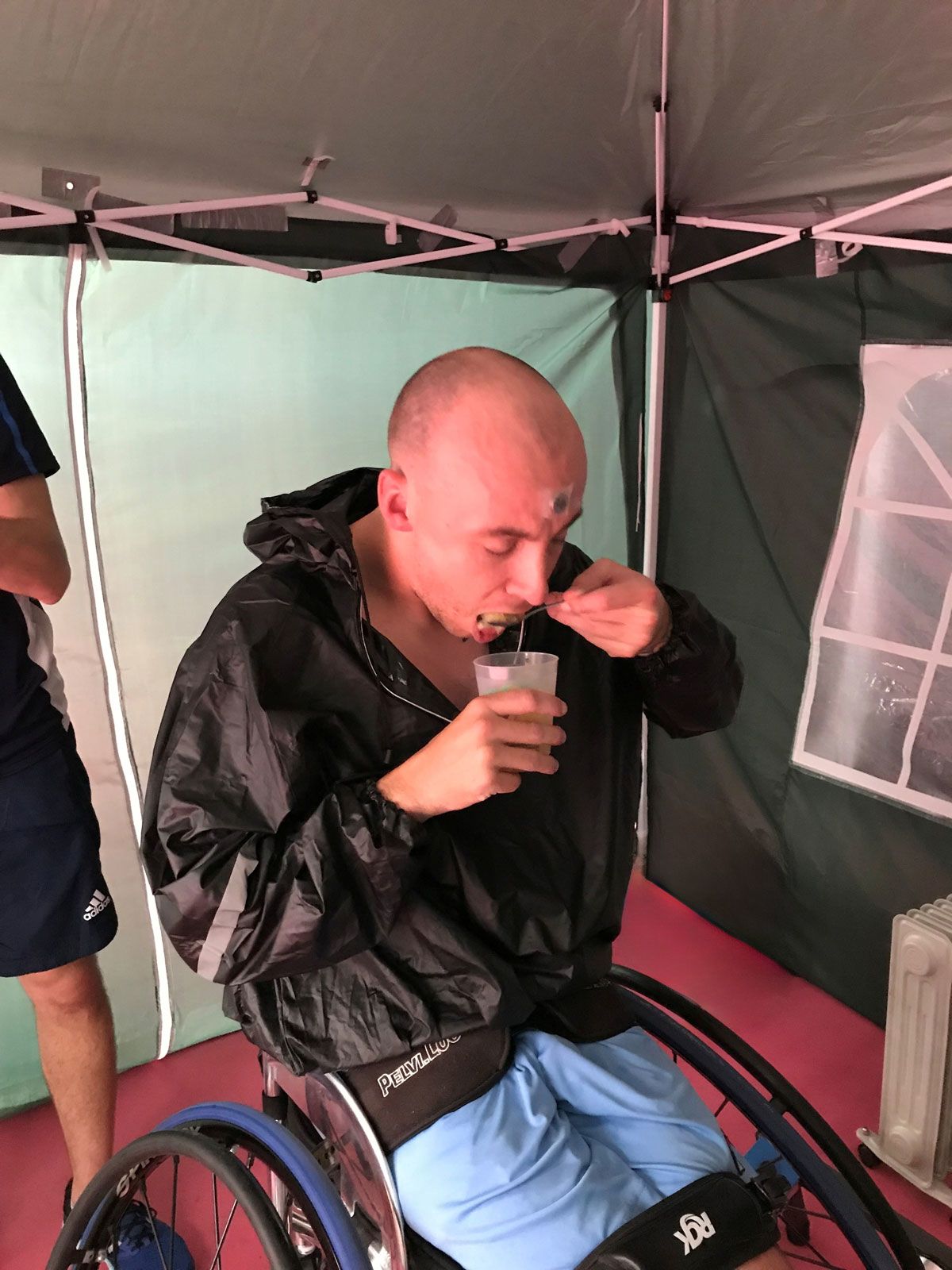 An athlete in a wheelchair sipping from a cup containing an ice slurpie