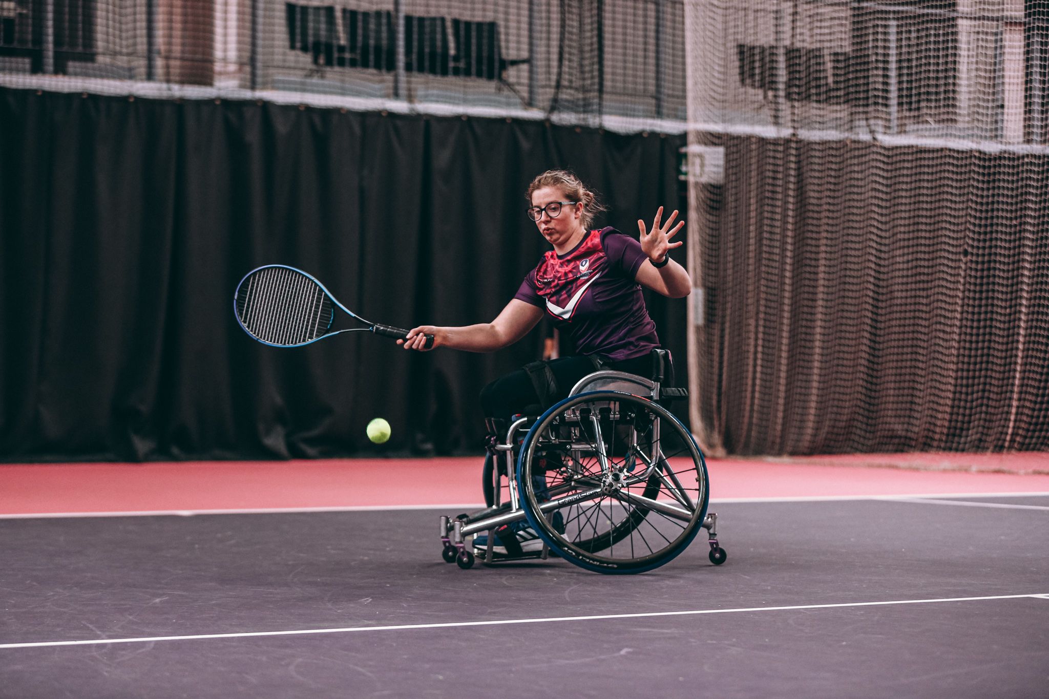 A female wheelchair tennis player on an indoor court