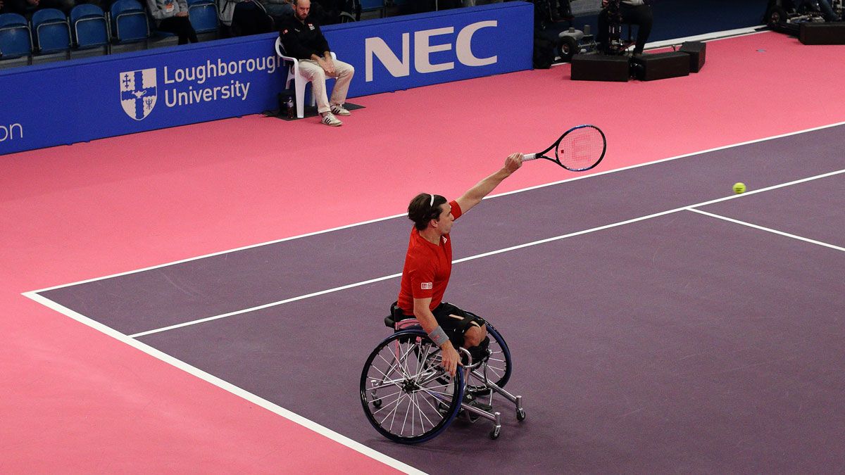 A wheelchair tennis player hitting a tennis ball on an indoor court