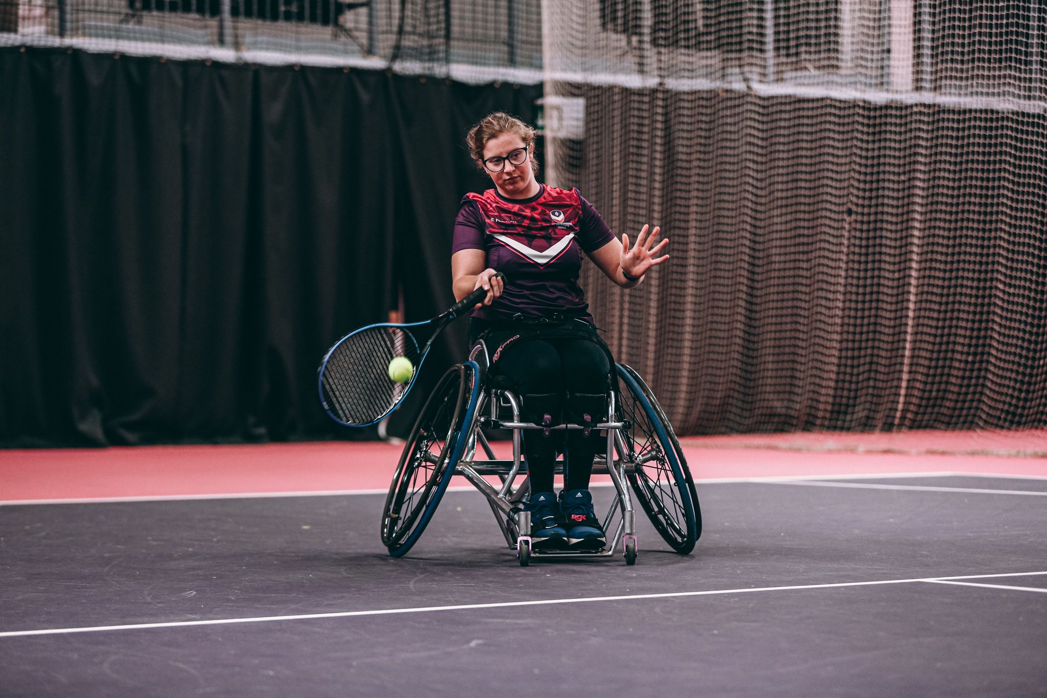 A female wheelchair tennis player on an indoor court